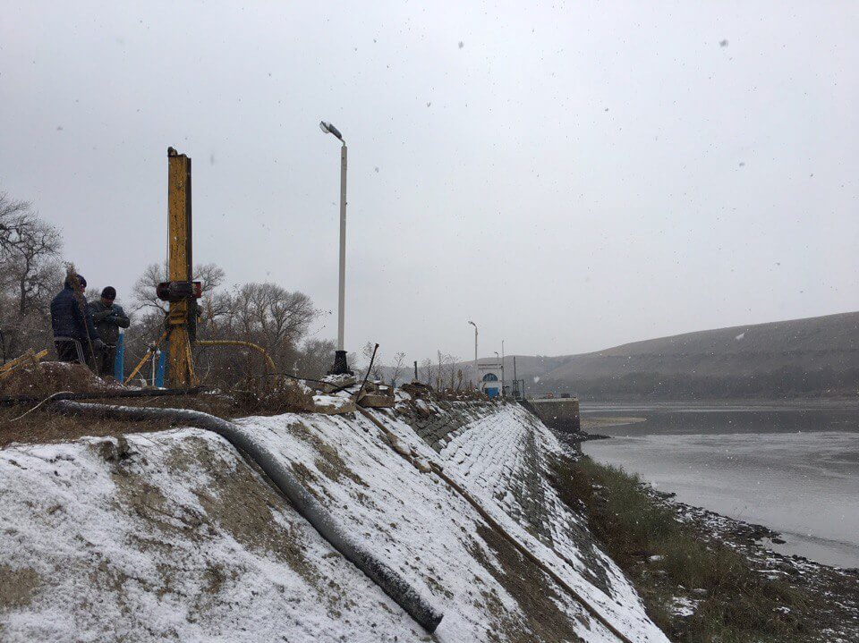 Буровые работы на дамбе у водоёма зимой
